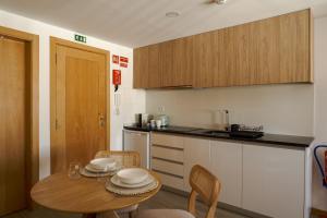 a kitchen with a wooden table and a table and chairs at VIELA Guest House Premium in Barcelos