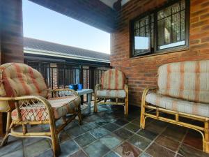 una stanza con due sedie e un muro di mattoni di Swallows Rest Cottage KZN a Scottburgh 1 altra foto