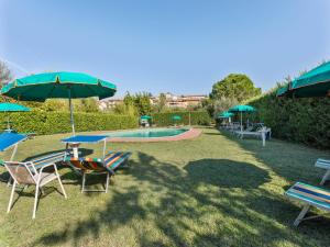 a group of chairs and tables with umbrellas and a pool at Cozy apartment with swimming pool and gym on Lake Trasimeno in Tuoro sul Trasimeno +11 photos