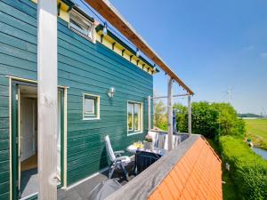 a blue house with a table and chairs on a deck at Beautiful Apartment in Callantsoog near Beach in Callantsoog
