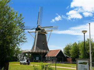 a windmill with a car parked in front of it at Beautiful Apartment in Callantsoog near Beach in Callantsoog +28 photos