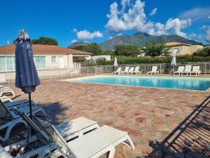 ein Swimmingpool mit einem blauen Sonnenschirm und Stühlen in der Unterkunft Mini Villa 200 m de la plage in Cervione