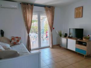 ein Wohnzimmer mit einem TV und einer Glasschiebetür in der Unterkunft Mini Villa 200 m de la plage in Cervione