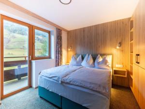 a bedroom with a bed with a large window at Lovely Apartment with Sauna, Ski Storage, Pool, Terrace in Wald im Pinzgau