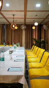 a row of tables with yellow chairs in a room at Hotel Skyking in Dehradun