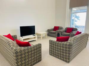 a living room with two couches and a flat screen tv at Seafield Tower Glenelg Apartment in Glenelg