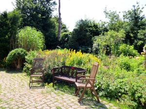 2 chaises et un banc dans un jardin dans l'établissement Rustic-style Apartment in Buschenhagen with Garden, à Buschenhagen