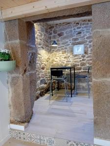 a stone walled room with a table and two chairs at Casa con encanto Ribeira Sacra in Sistín