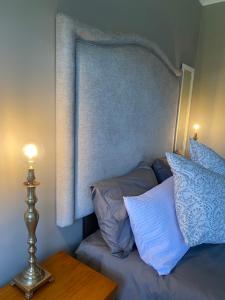 Una cama con almohadas azules y una lámpara en una mesa. en The Perfect Spot, en Welgelegen