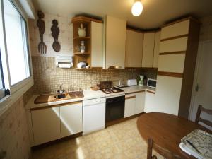 eine Küche mit weißen Schränken und einem Waschbecken und einem Tisch in der Unterkunft Saint-Germain Beach Bliss in Saint-Germain-sur-Ay