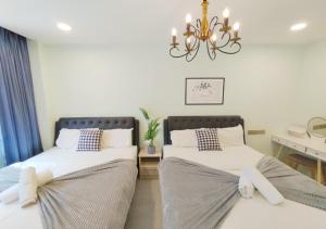 two beds in a room with a chandelier at Dim Sum Homestay in Ipoh