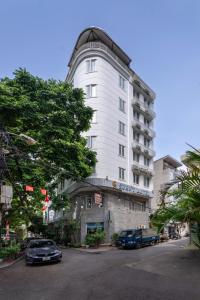 a white building with cars parked in front of it at Sunny Hotel in Hanoi