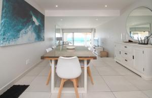 a dining room with a table and a white chair at 1001 Bermudas - Seaviews & beach access - Modern 3BR Umhlanga in Durban +22 photos