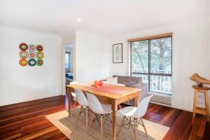 a dining room with a wooden table and white chairs at Bawley retreat in Bawley Point