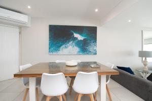 a dining room with a wooden table and white chairs at 1001 Bermudas - Seaviews & beach access - Modern 3BR Umhlanga in Durban