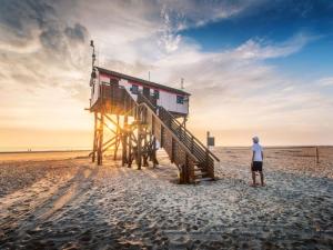 a man standing next to a lifeguard house on the beach at Semi-detached house in St Peter-Ording in Sankt Peter-Ording +38 photos