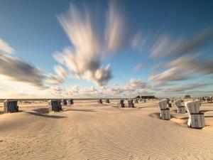 a group of chairs sitting in the sand on a beach at Semi-detached house in St Peter-Ording in Sankt Peter-Ording