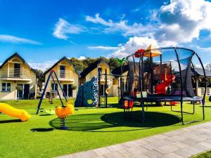 einen Park mit einem Spielplatz mit Rutschen und Schaukeln in der Unterkunft Holiday resort with Pool, Whirlpool, Sauna, Ustronie Morskie in Ustronie Morskie
