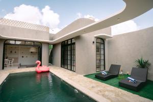 a house with a swimming pool with a pink swan in the water at SOOJIWA VILLA by Taman Bali in Dalung