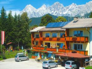 un edificio con auto parcheggiate in un parcheggio con montagne di Apartments home Hermann, Ramsau am Dachstein a Ramsau am Dachstein