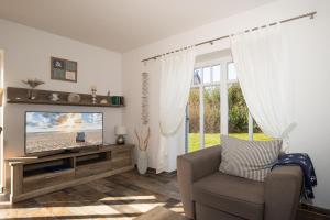 a living room with a television and a chair at Haus Ostseestrand in Lancken