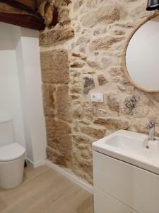 a bathroom with a white sink and a stone wall at Duplex en Ribeira Sacra in Sistín