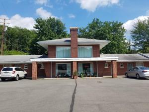 ein Backsteingebäude mit Autos auf einem Parkplatz in der Unterkunft Melody Motor Lodge in Connellsville