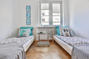 Habitación con 2 camas, mesa y 2 ventanas. en Apartament Batory, en Gdynia