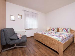 a bedroom with a bed and a chair at Cozy Ski Base with Garden in Breitenbrunn
