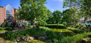 a pond in a park with trees and buildings at Hotel Heidehof garni in Büdelsdorf
