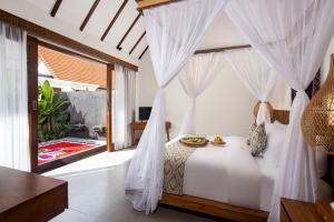 a bedroom with a bed with white curtains at Jenna Villa by GenuineHost in Ubud