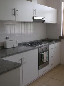 a kitchen with white cabinets and a stove top oven at Alojamento Rural de Covelas in Covelas