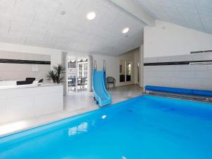a large swimming pool with a blue pool slide at 24 person holiday home in Blåvand in Blåvand