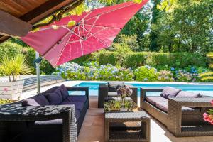 TarnosにあるAu coeur des Pinsの赤い傘が置かれたプールサイドのパティオ