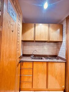 a small kitchen with wooden cabinets and a sink at فندق غزالة برفكت توصيل مجاني للحرم - Ghazala Perfect Hotel Free shuttle service to the Haram in Makkah