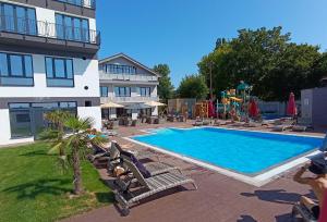 a swimming pool with chairs and a playground next to a building at Hotel Sun in Senec