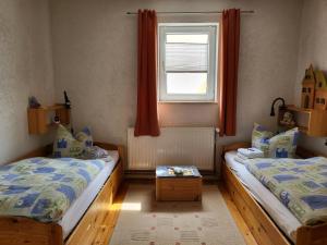two beds in a small room with a window at Ferienwohnung in den Hüttenroder Bergen in Hüttenrode
