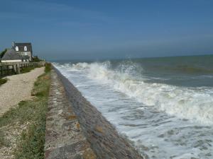 a wave breaking on a wall next to the ocean at Normandy Family Escape in Saint-Floxel