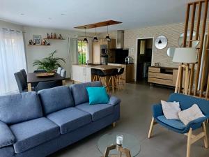 a living room with a blue couch and a kitchen at Villa Testarouch - Proche Bordeaux & Arcachon in Mios