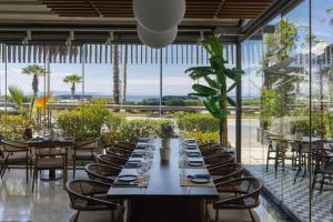 a dining room with tables and chairs and windows at Coral Hotel Athens in Athens
