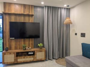 a living room with a flat screen tv on a wooden wall at Poolside Farm Retreat wit Garden in Hosūr