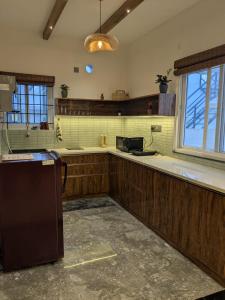 a kitchen with wooden cabinets and a sink and a refrigerator at Poolside Farm Retreat wit Garden in Hosūr
