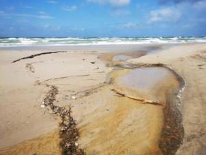 a sandy beach with waves and the ocean at 6 person holiday home in Brovst in Brovst