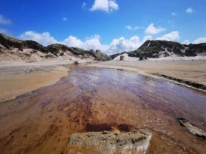 a muddy beach with a rock in the water at 6 person holiday home in Brovst in Brovst