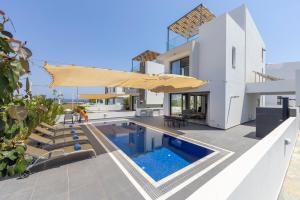 a white house with a swimming pool and an umbrella at Seaside Emerald in Paralimni