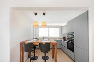 een keuken met een houten tafel en zwarte stoelen bij Monaco border - Balcon vue mer - DD in Beausoleil