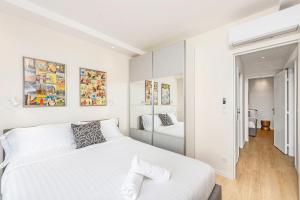 een witte slaapkamer met een bed en een spiegel bij Monaco border - Balcon vue mer - DD in Beausoleil