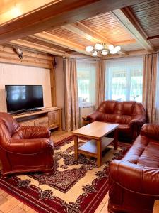 a living room with leather furniture and a flat screen tv at Смерековий двір in Slavske