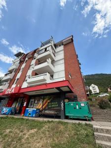 a tall building with a sign in front of it at Studio Apartman Gracia in Plužine