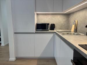 eine Küche mit weißen Schränken und einer Mikrowelle in der Unterkunft Dvojizbový apartmán v centre in Poprad
